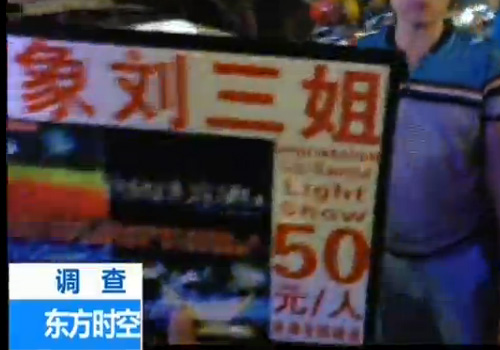在西街上，很多人举着印象刘三姐50元票价的牌子坑骗游客